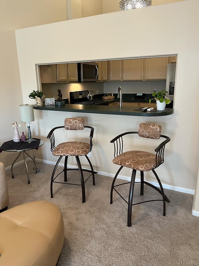 28848 5 Mile Rd Unit 11, Livonia, MI 48154 - kitchen with carpet flooring, dark countertops, stainless steel appliances, a kitchen breakfast bar, and baseboards