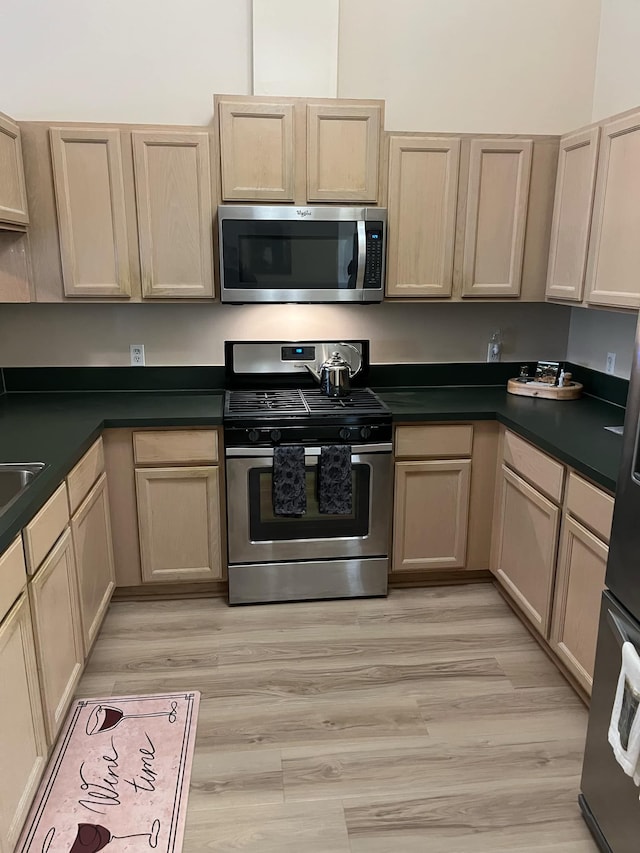 28848 5 Mile Rd Unit 11, Livonia, MI 48154 - kitchen with stainless steel appliances, light brown cabinetry, dark countertops, and light wood-style floors