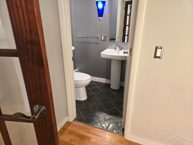 8570 Hornbeam Ln, Saginaw, MI 48603 - half bathroom featuring toilet, baseboards, wood finished floors, and a sink