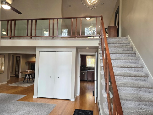 8570 Hornbeam Ln, Saginaw, MI 48603 - stairway with a high ceiling, wood finished floors, a ceiling fan, a baseboard heating unit, and baseboards