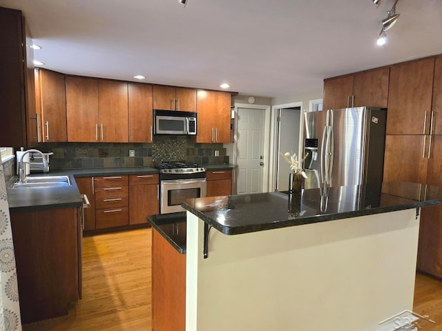 8570 Hornbeam Ln, Saginaw, MI 48603 - kitchen featuring light wood-style flooring, brown cabinets, a sink, dark countertops, and appliances with stainless steel finishes