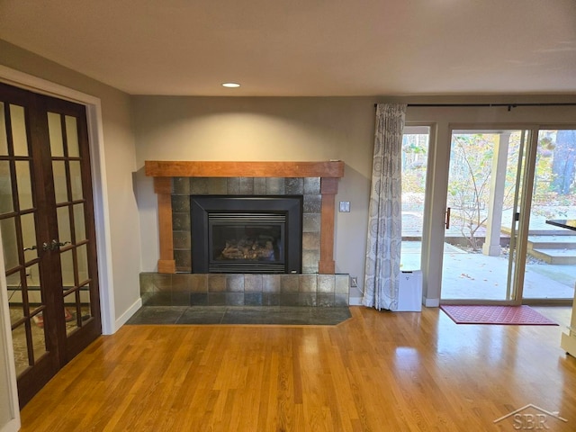 8570 Hornbeam Ln, Saginaw, MI 48603 - unfurnished living room with baseboards, a tile fireplace, french doors, and wood finished floors