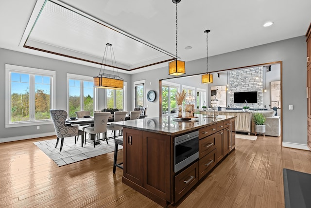 5744 Wyndam Ln, Brighton, MI 48116 - kitchen with a tray ceiling, hardwood / wood-style floors, open floor plan, a center island with sink, and stainless steel microwave