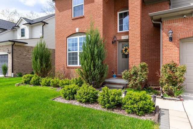 property entrance with a yard, a garage, and brick siding