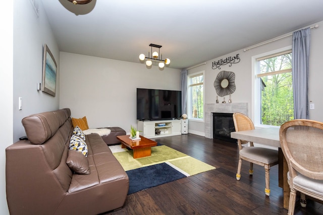 living area featuring baseboards, a notable chandelier, a tile fireplace, and dark wood-style floors