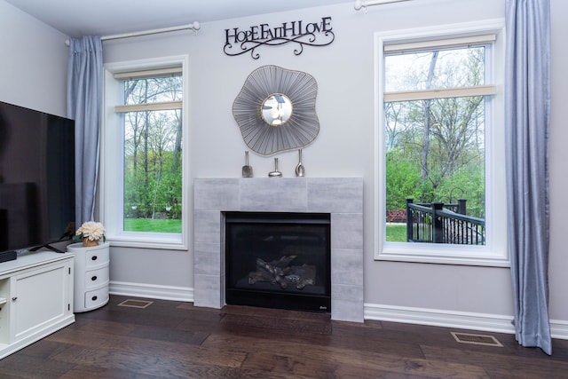 living room with dark wood-type flooring, baseboards, visible vents, and a fireplace