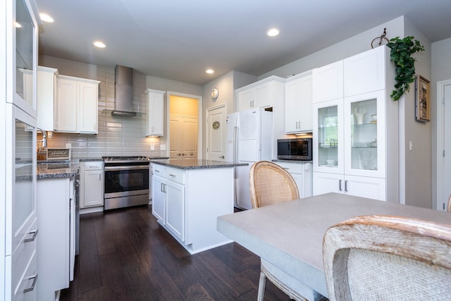 kitchen featuring dark wood-style flooring, wall chimney exhaust hood, a kitchen island, stainless steel appliances, and white cabinets