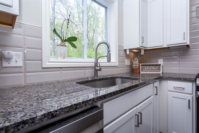 kitchen with stainless steel dishwasher, plenty of natural light, white cabinets, and a sink
