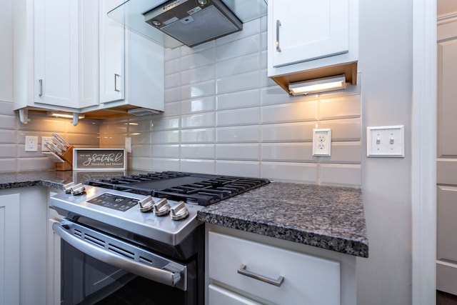 kitchen featuring dark stone countertops, stainless steel gas range oven, range hood, white cabinets, and backsplash