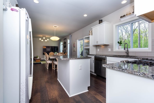 kitchen with freestanding refrigerator, dishwasher, dark wood finished floors, a sink, and tasteful backsplash