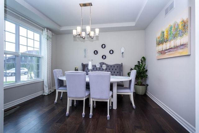dining space featuring a raised ceiling, a notable chandelier, visible vents, and dark wood-style flooring
