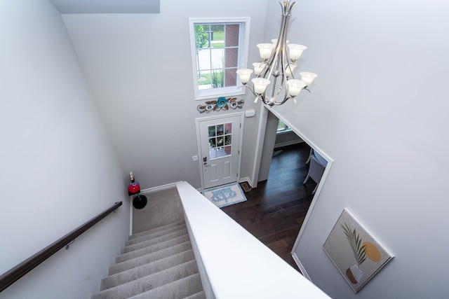 staircase with a chandelier and wood finished floors
