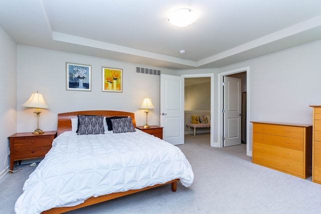 bedroom featuring light colored carpet, a raised ceiling, and visible vents