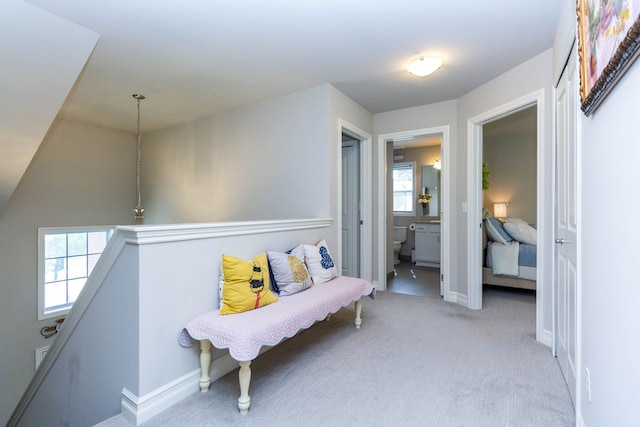 sitting room featuring baseboards, an upstairs landing, and carpet