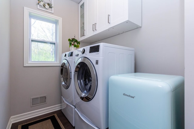 laundry area featuring baseboards, visible vents, cabinet space, and washer and clothes dryer