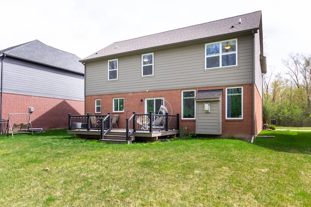 back of house featuring a yard, a deck, and brick siding