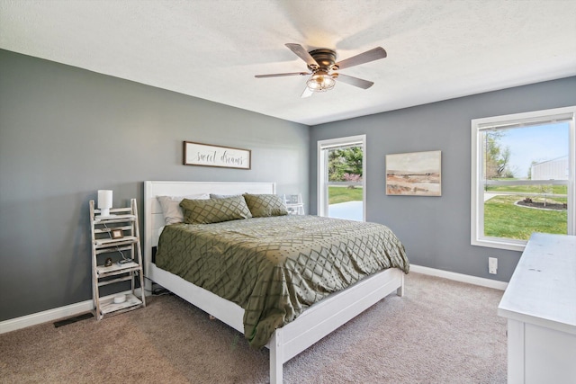 carpeted bedroom featuring a textured ceiling, baseboards, and a ceiling fan