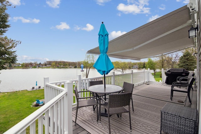 wooden deck with a yard, a water view, and outdoor dining space