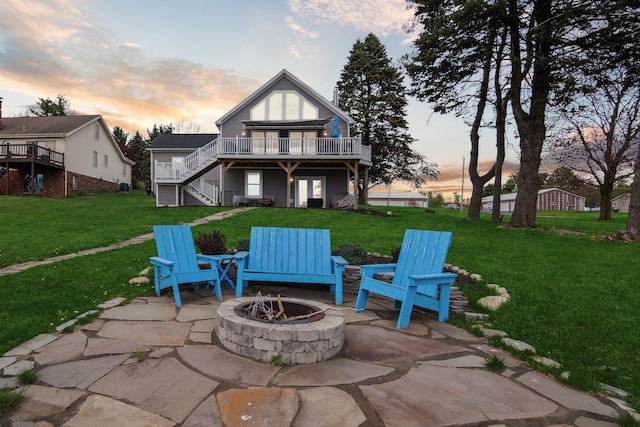 back of house featuring a lawn, stairs, a patio area, a wooden deck, and a fire pit
