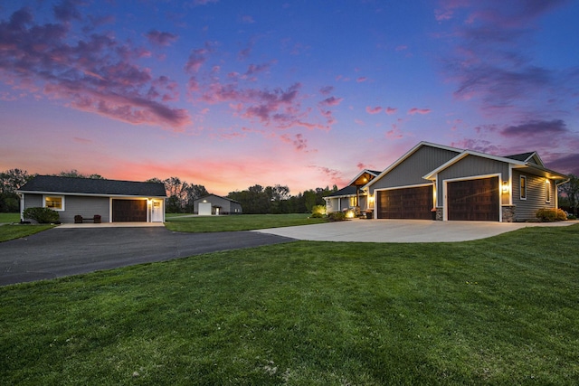 view of front facade with a lawn, an attached garage, stone siding, and driveway