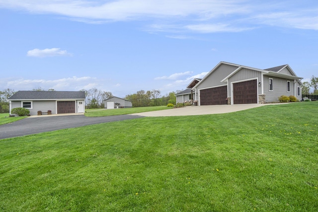 view of home's exterior featuring a lawn, stone siding, an outbuilding, and driveway