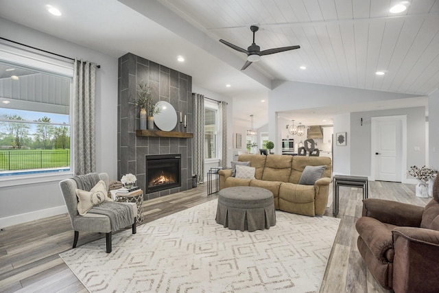living area featuring a tile fireplace, wood finished floors, ceiling fan with notable chandelier, lofted ceiling, and recessed lighting