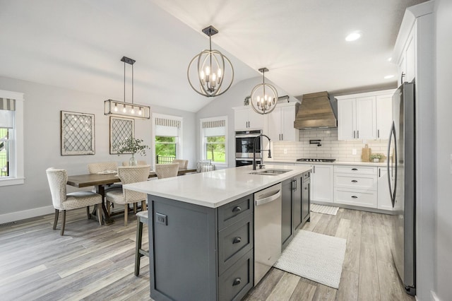 kitchen with a sink, white cabinets, custom range hood, and appliances with stainless steel finishes