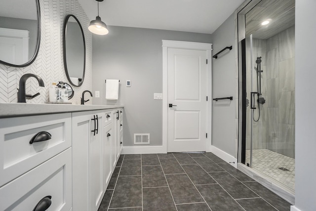 full bathroom featuring a tile shower, visible vents, baseboards, tile patterned flooring, and vanity