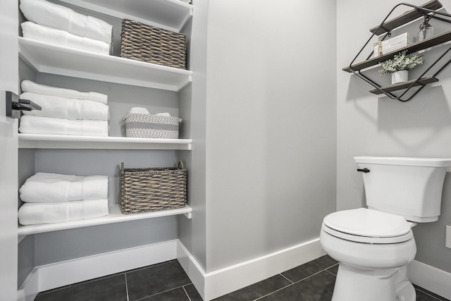bathroom with toilet, baseboards, and tile patterned flooring