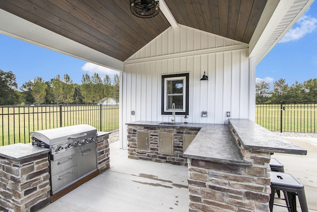 view of patio / terrace featuring a sink, fence, an outdoor kitchen, and a grill