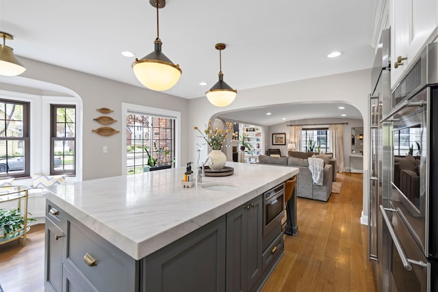 33 Sylvan Ave, Pleasant Ridge, MI 48069 - kitchen featuring recessed lighting, a sink, open floor plan, wood finished floors, and arched walkways