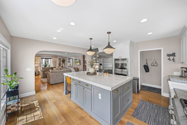 33 Sylvan Ave, Pleasant Ridge, MI 48069 - kitchen featuring an island with sink, arched walkways, gray cabinets, and appliances with stainless steel finishes