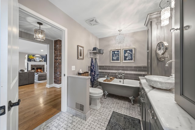 33 Sylvan Ave, Pleasant Ridge, MI 48069 - bathroom with vanity, a brick fireplace, a freestanding bath, and visible vents