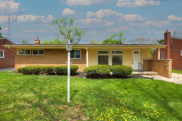ranch-style house featuring a front lawn, brick siding, and a chimney