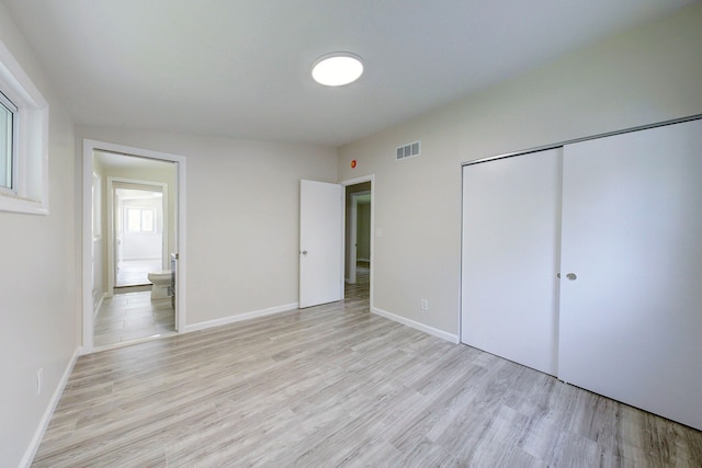 unfurnished bedroom with light wood finished floors, a closet, and baseboards