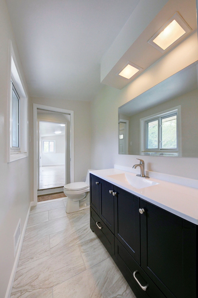 bathroom with toilet, vanity, and baseboards