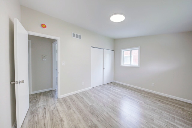 unfurnished bedroom featuring light wood-style floors, baseboards, and a closet