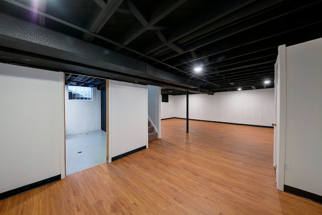 basement featuring stairway, wood finished floors, and baseboards