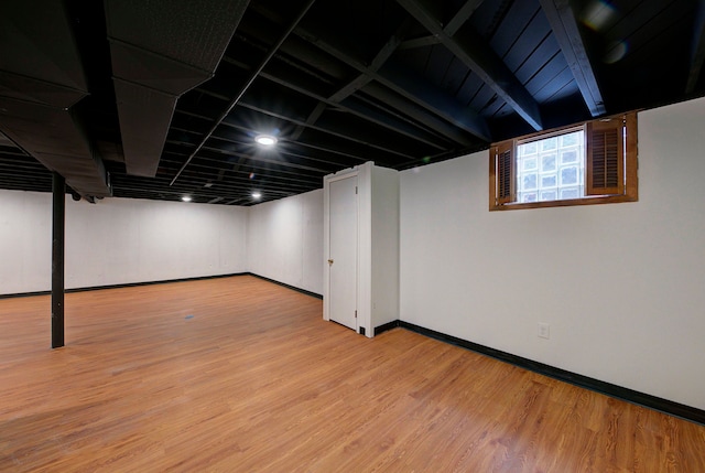 basement featuring baseboards and light wood finished floors