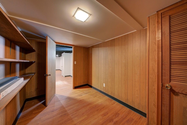 finished basement featuring light wood-type flooring, wooden walls, and baseboards