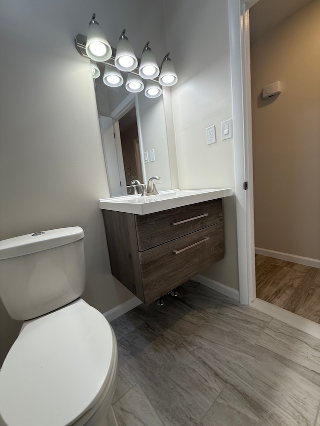 bathroom with toilet, vanity, and baseboards