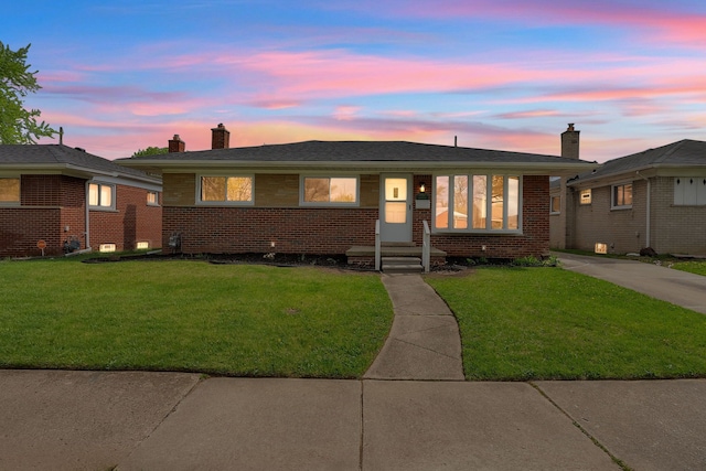 view of front of property with a chimney, driveway, brick siding, and a lawn