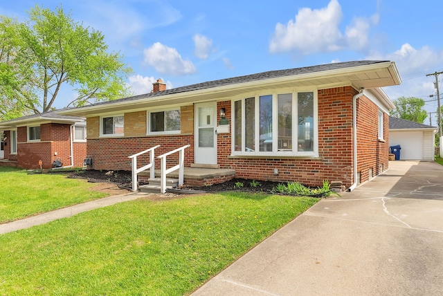 single story home featuring brick siding, a chimney, a front yard, and a detached garage