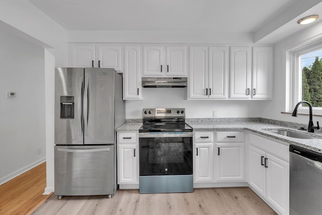 kitchen featuring light wood-style flooring, a sink, stainless steel appliances, light stone countertops, and under cabinet range hood