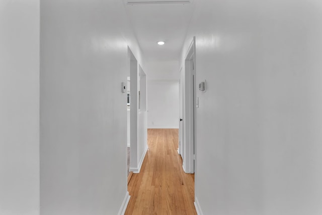 corridor featuring baseboards, recessed lighting, and light wood-type flooring