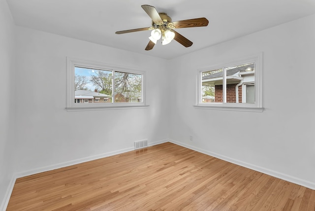 empty room featuring a wealth of natural light, baseboards, and light wood-style floors