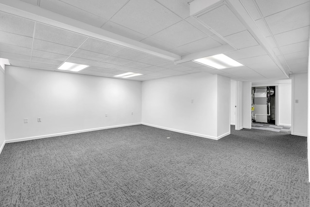 unfurnished room with heating unit, dark colored carpet, baseboards, and a paneled ceiling