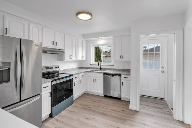 kitchen with under cabinet range hood, a wealth of natural light, appliances with stainless steel finishes, and a sink