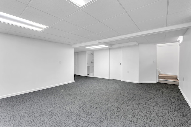 finished basement with a paneled ceiling, baseboards, and carpet floors