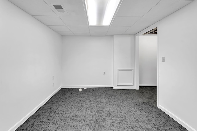 empty room with a paneled ceiling, carpet flooring, visible vents, and baseboards